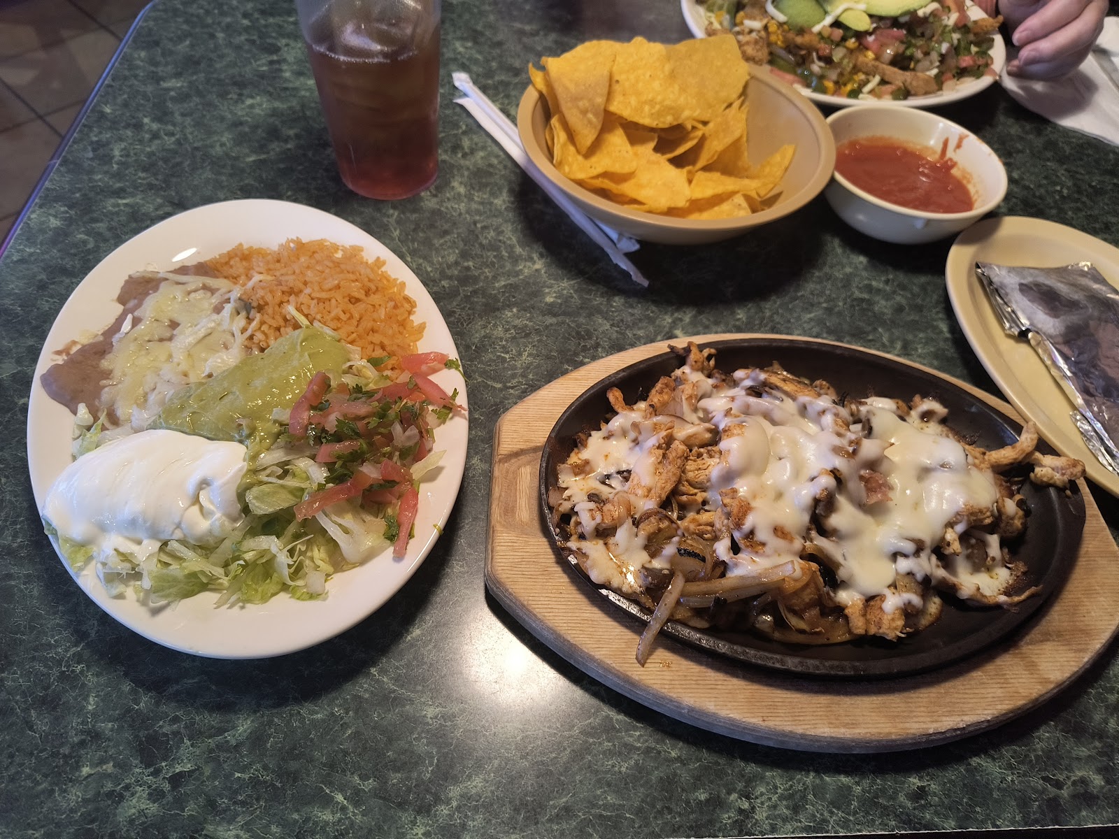 Sizzling chicken fajitas with rice, beans, salad, chips and salsa